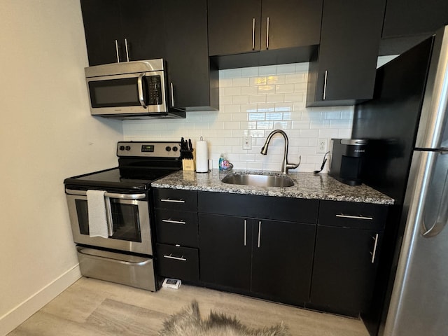 kitchen featuring sink, light stone countertops, stainless steel appliances, and tasteful backsplash