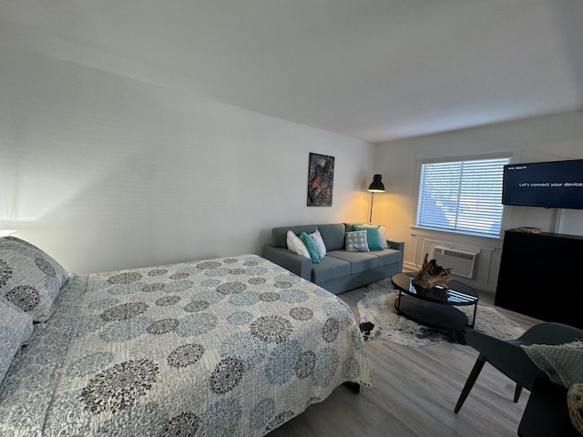 bedroom with light wood-type flooring and an AC wall unit