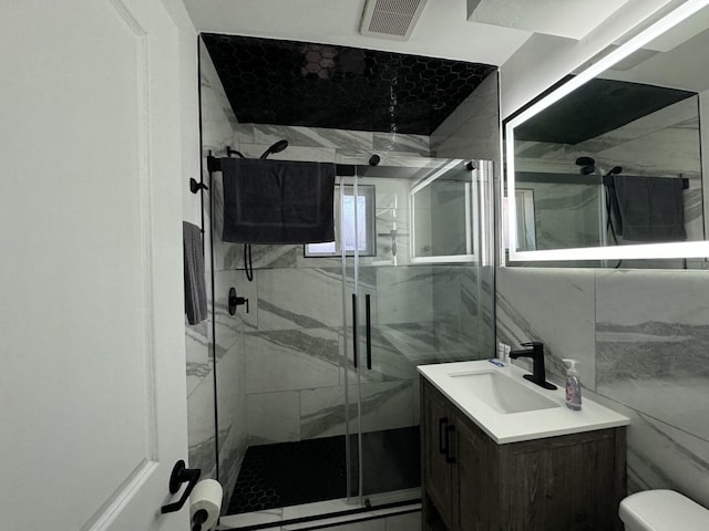 bathroom with vanity, toilet, walk in shower, and tile walls