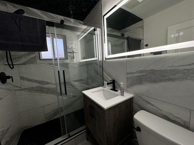 bathroom featuring vanity, toilet, walk in shower, and tile walls