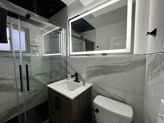 bathroom featuring walk in shower, vanity, tile walls, and toilet