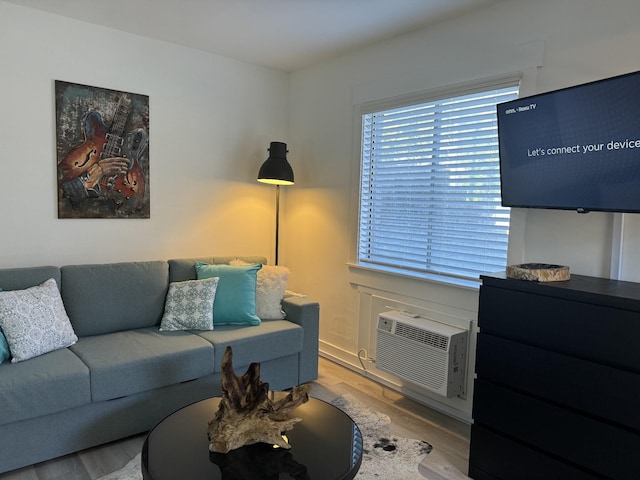 living room featuring a wall mounted air conditioner and light hardwood / wood-style flooring