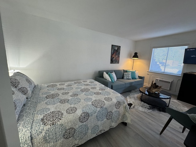 bedroom with a wall mounted AC and wood-type flooring