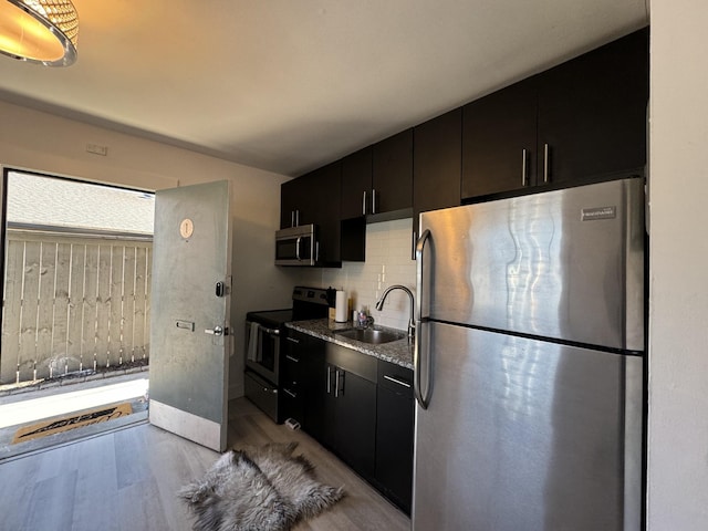 kitchen featuring backsplash, sink, light wood-type flooring, and stainless steel appliances