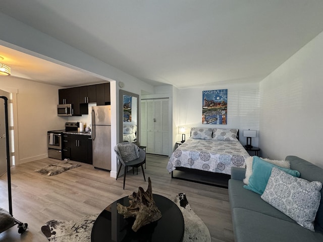 bedroom featuring light hardwood / wood-style floors, stainless steel refrigerator, and a closet