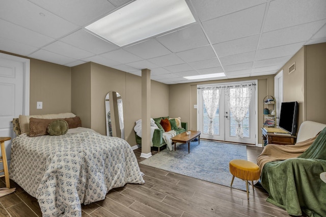 bedroom with a paneled ceiling, wood-type flooring, and french doors