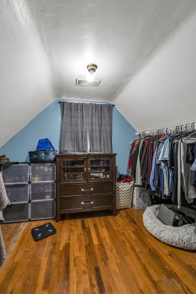 walk in closet with wood-type flooring and vaulted ceiling