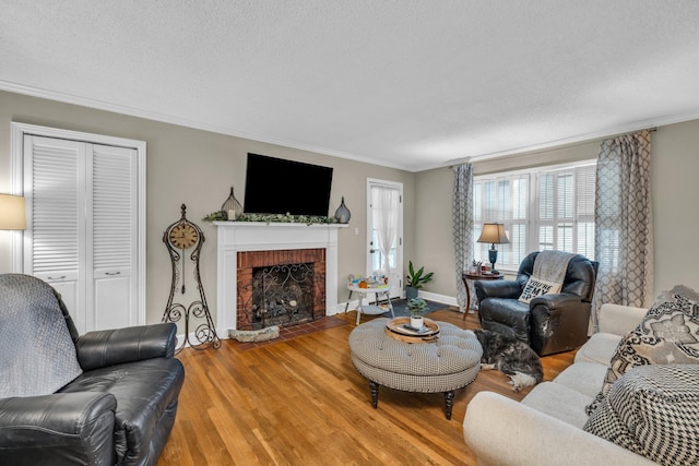 living room with a fireplace, hardwood / wood-style floors, a textured ceiling, and ornamental molding