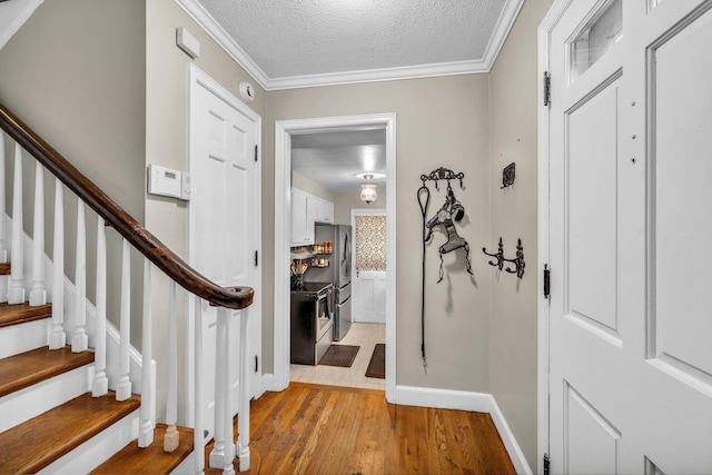 foyer with a textured ceiling, light hardwood / wood-style flooring, and crown molding