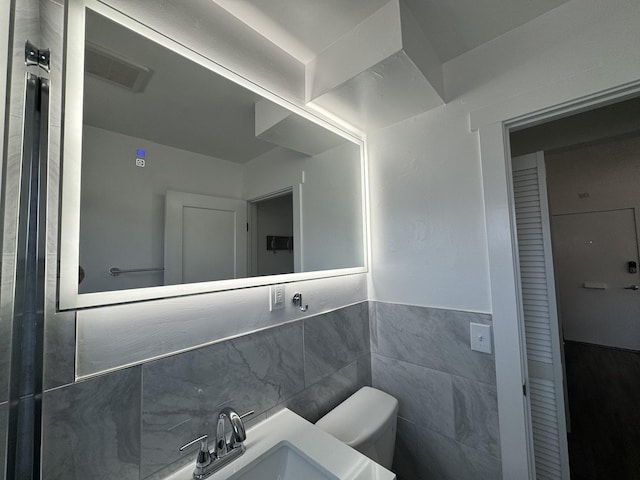 bathroom featuring vanity, tile walls, and toilet