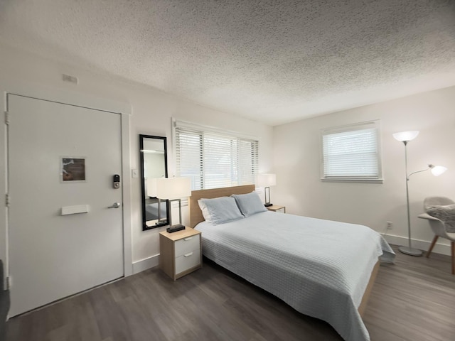 bedroom with dark hardwood / wood-style flooring and a textured ceiling