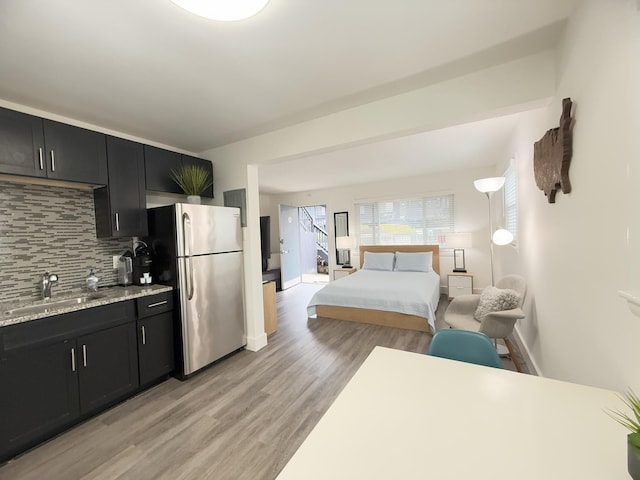 bedroom featuring stainless steel fridge, sink, and light wood-type flooring