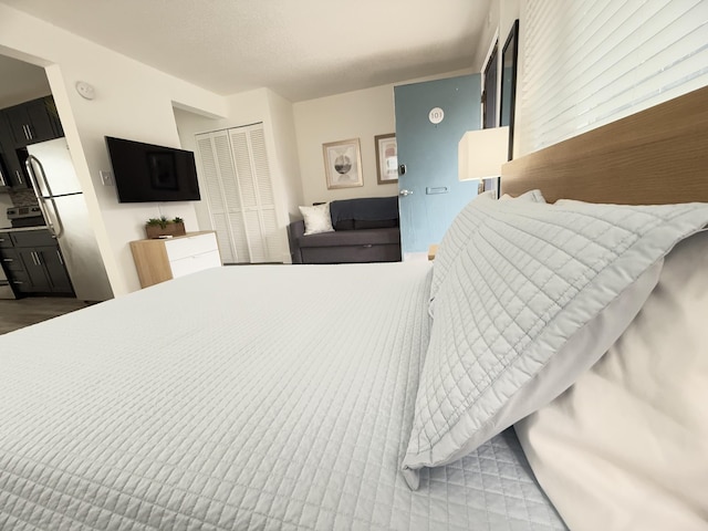 bedroom featuring stainless steel refrigerator and a closet