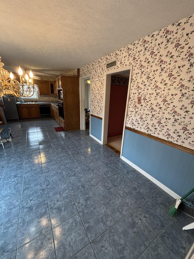 interior space with an inviting chandelier, a textured ceiling, and dark tile patterned floors