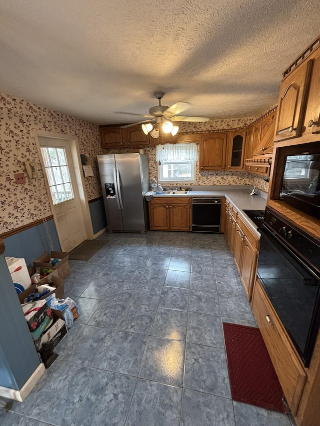 kitchen featuring ceiling fan, a healthy amount of sunlight, a textured ceiling, and black appliances