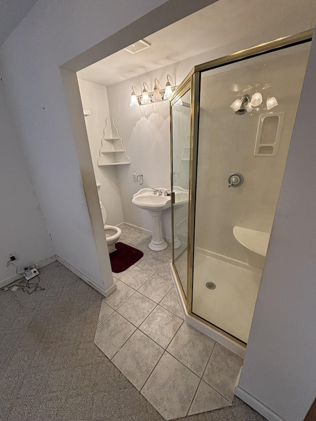 bathroom with toilet, a shower with door, and tile patterned flooring