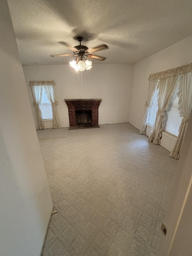 unfurnished living room with ceiling fan, a textured ceiling, and a fireplace