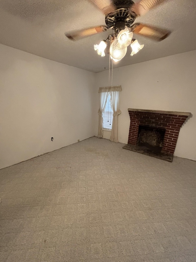 unfurnished living room with ceiling fan, carpet flooring, a fireplace, and a textured ceiling