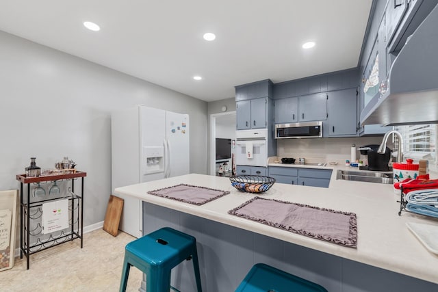 kitchen featuring sink, a breakfast bar area, kitchen peninsula, blue cabinets, and oven