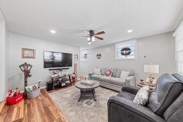 living room featuring ceiling fan, wood-type flooring, and a textured ceiling