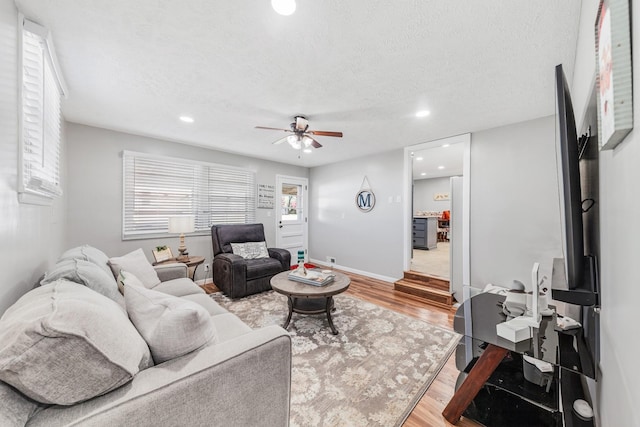 living room featuring ceiling fan, wood-type flooring, and a textured ceiling