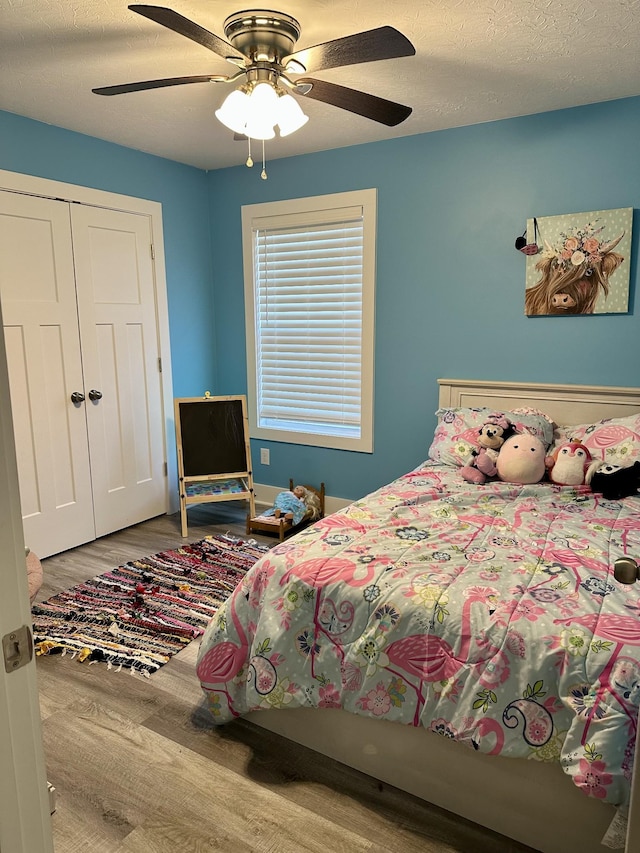 bedroom with hardwood / wood-style flooring, ceiling fan, a textured ceiling, and a closet