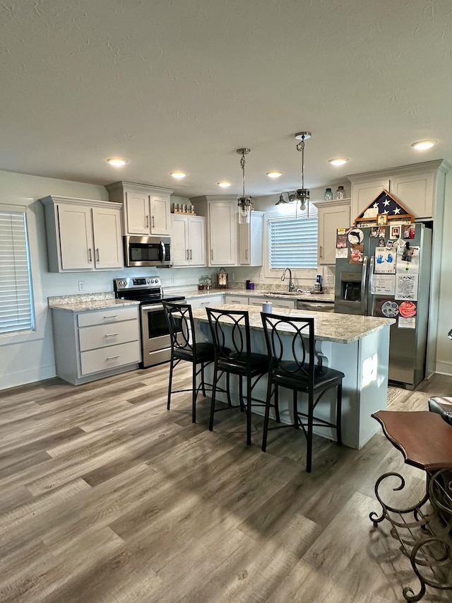 kitchen featuring pendant lighting, a center island, light hardwood / wood-style floors, and appliances with stainless steel finishes