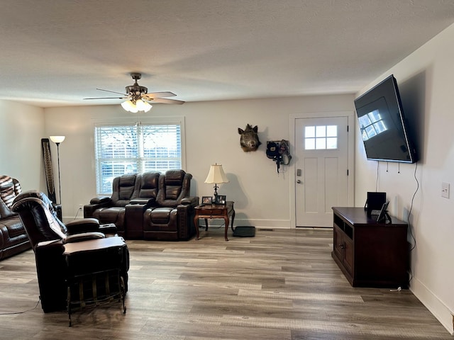 living room featuring ceiling fan, plenty of natural light, a textured ceiling, and light wood-type flooring