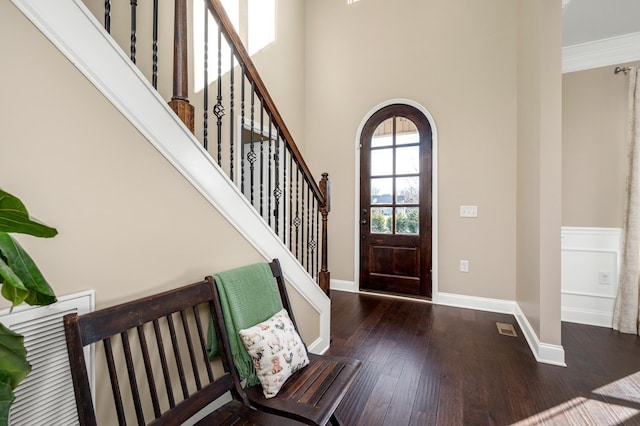 foyer entrance featuring a towering ceiling, dark hardwood / wood-style flooring, and crown molding