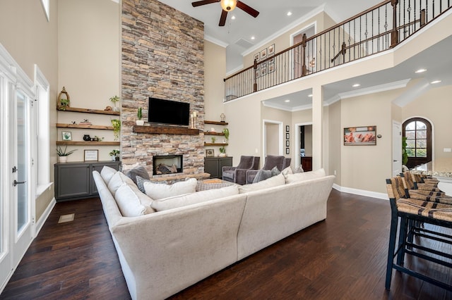 living room with dark hardwood / wood-style floors, a stone fireplace, and a high ceiling