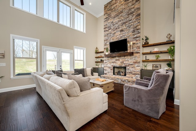 living room with french doors, a towering ceiling, ornamental molding, dark hardwood / wood-style floors, and a stone fireplace