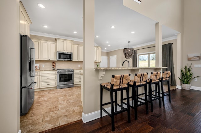 kitchen featuring light stone counters, light hardwood / wood-style flooring, cream cabinetry, and appliances with stainless steel finishes