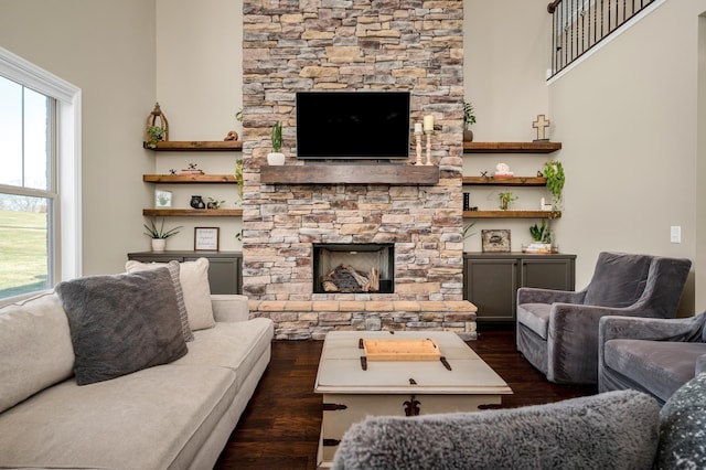 living room with dark hardwood / wood-style floors and a stone fireplace