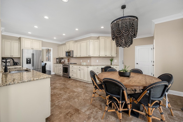 kitchen featuring cream cabinetry, appliances with stainless steel finishes, an inviting chandelier, and sink