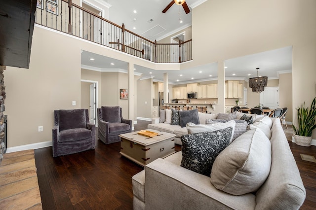 living room with dark hardwood / wood-style flooring, a towering ceiling, ceiling fan, and ornamental molding