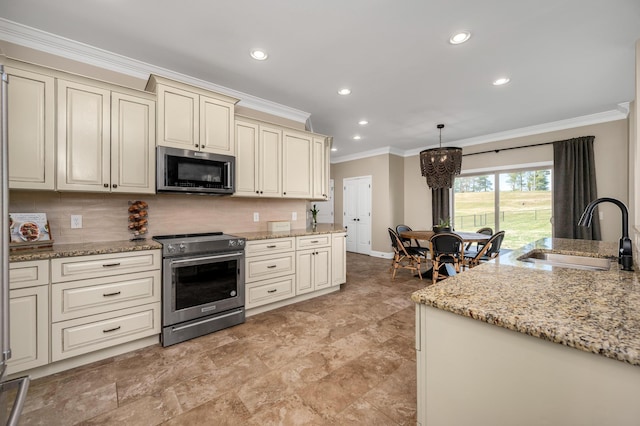 kitchen featuring pendant lighting, backsplash, sink, appliances with stainless steel finishes, and cream cabinetry