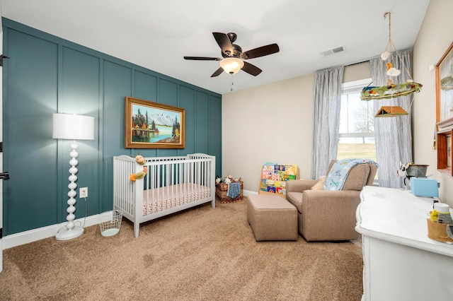 bedroom with ceiling fan, light colored carpet, and a nursery area