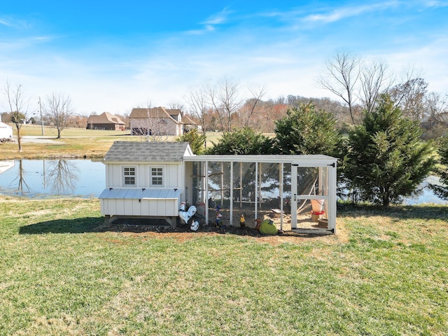 exterior space with a lawn, a water view, and an outdoor structure