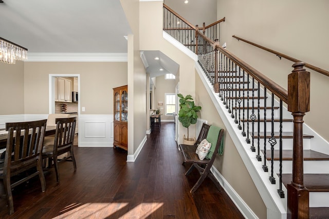 entrance foyer with dark hardwood / wood-style flooring, ornamental molding, and a high ceiling