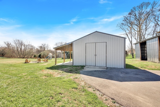 view of outdoor structure with a carport and a lawn