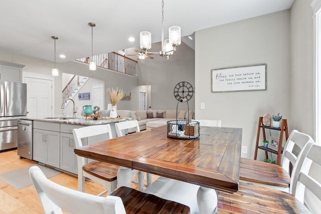 dining space featuring ceiling fan, light hardwood / wood-style floors, a towering ceiling, and sink