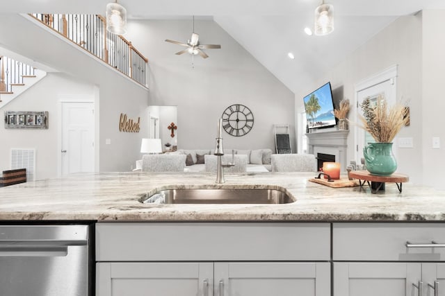 kitchen featuring ceiling fan, sink, light stone counters, high vaulted ceiling, and white cabinets