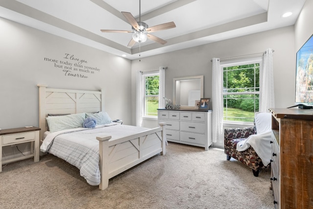 carpeted bedroom featuring a raised ceiling and ceiling fan