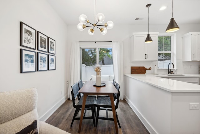 dining space with plenty of natural light, dark wood-type flooring, sink, and a chandelier