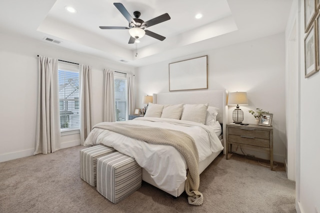 carpeted bedroom featuring a raised ceiling and ceiling fan