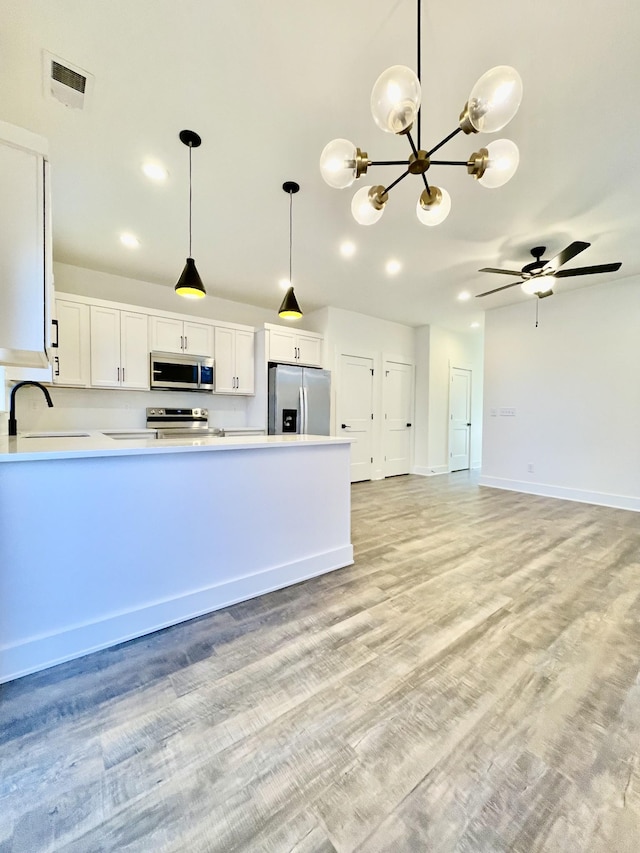 kitchen featuring white cabinets, ceiling fan with notable chandelier, sink, decorative light fixtures, and stainless steel appliances