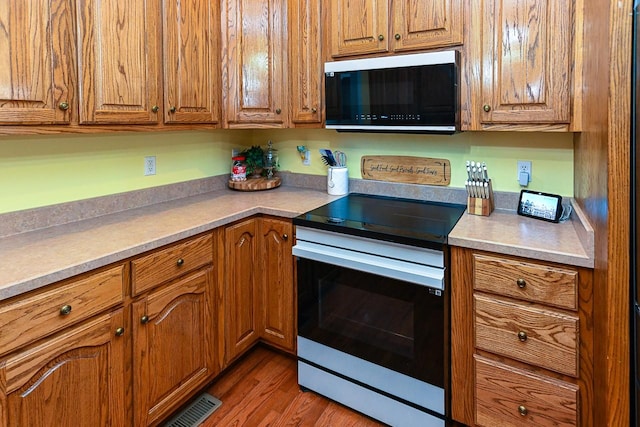 kitchen with hardwood / wood-style flooring and stainless steel range with electric cooktop