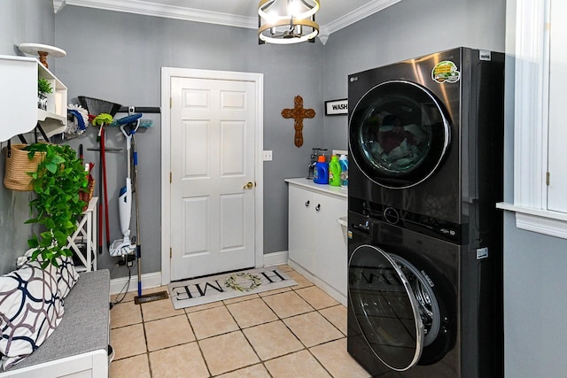 laundry area with an inviting chandelier, ornamental molding, stacked washer / drying machine, and light tile patterned floors