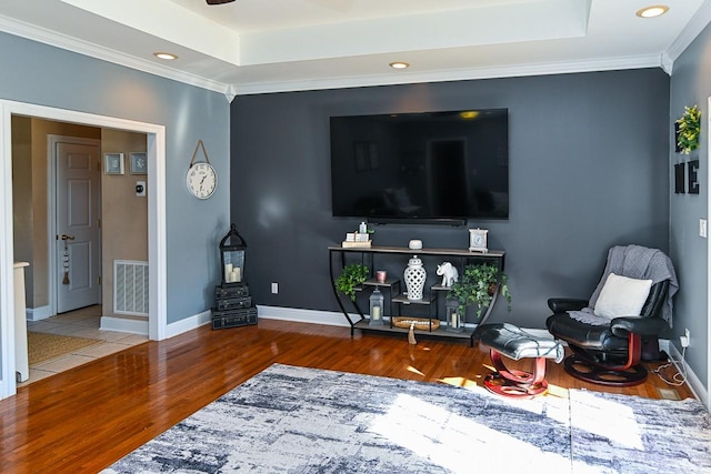 living area featuring ornamental molding, wood-type flooring, and a tray ceiling