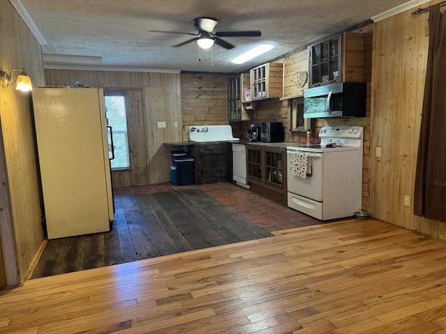 kitchen featuring a textured ceiling, wood walls, hardwood / wood-style floors, and white appliances